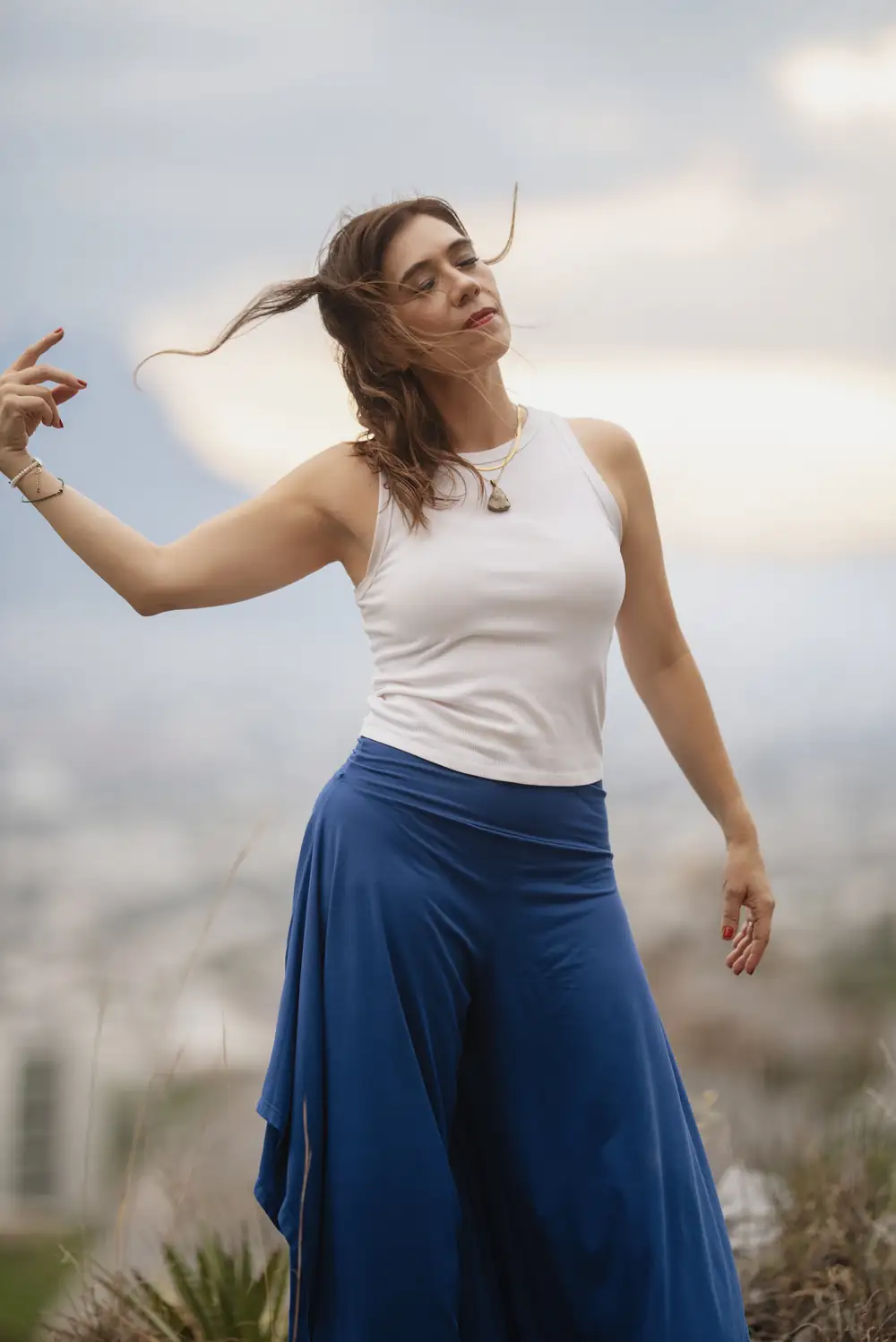 Cici con los brazos abiertos al viento en lo alto de un cerro
